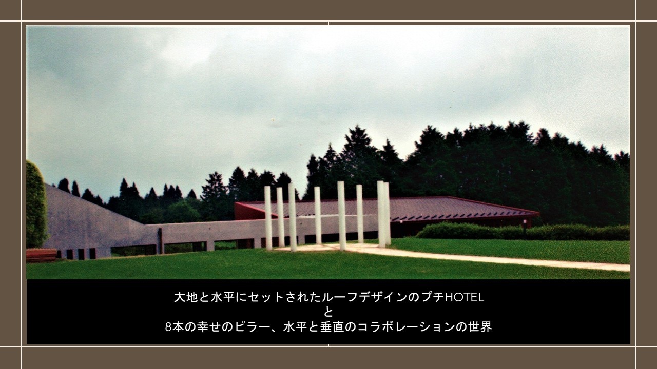 芝生の大地に立つ8本の白いピラーと周囲の建築